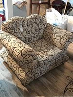 Full front and side view of the upholstered armchair showing the patterned fabric and cushion details.