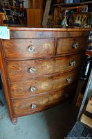 Front view of the antique dresser showing wood grain, glass knobs, and five drawers.