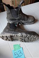 Side and sole view of the boots showing scuffed brown leather, black elastic sides, and dirty soles with tread pattern.
