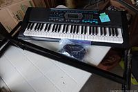 Full keyboard with stand and accessories on table, with power cable in plastic bag