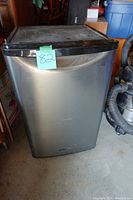 Front view of the mini fridge showing stainless steel door with some scratches and dents.