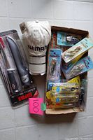 Overview of entire set showing fishing lures in box, Shimano hat placed on top, and fillet knife package visible, with pink lot number card.