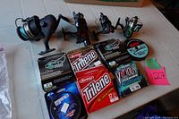 Four Shakespeare fishing reels with several spools of fishing line displayed on a table.