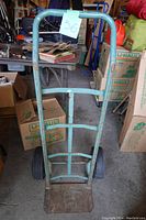 Front view of the blue metal fridge dolly showing curved handle and lift plate.