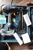 Mastercraft air-powered finishing nailer, brad nailer, and stapler tool in blue case, showing tool with attached air hose fitting and accessory parts inside case.