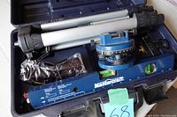 Mastercraft laser level device, aluminum tripod, and safety glasses inside black hard plastic carry case shown from above.