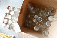 Box containing multiple clear glass preserving jars in varying amounts and sizes.