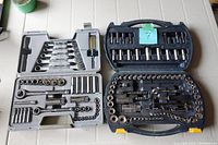 Two open socket sets showing multiple sockets, ratchets, wrench tools in black and gray plastic cases.