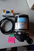 Photo of Burke sump pump showing the pump body, electrical cord, and packaging on table.