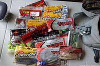 Soft worm fishing lures in original packaging laid out with canvas bag