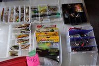 Various open tackle boxes and containers with assorted fishing lures, hooks, and accessories.