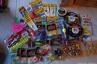 Overview of the fishing tackle collection showing multiple soft plastic baits, hooks, fishing line spools, and lures arranged on a table.