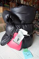 Sleeping bag rolled and secured with visible black exterior and red interior lining, showing the label attached to the zipper area.