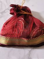 Red decorative pouch containing the bangles, showing the fabric and gold trim