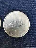 Close-up photo of one 1981 Canadian silver dollar coin showing front with Voyageur canoe design and date 1981.
