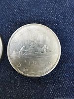 Close-up of one 1981 Canadian silver dollar coin showing the Voyageur design with two men paddling a canoe, the year, and inscriptions clearly visible.