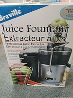 Box front of Breville Juice Fountain showing brand, product name, and image of juicer with fruits and vegetables.