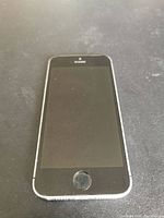 Front view of the black front panel with home button, screen off showing some smudges or dirt.