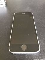 Front view of space gray Apple iPhone SE showing screen with Home Button on black surface.