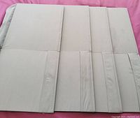 Four flat fabric storage cubbies folded flat, showing backside and bottom flap areas.