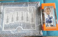 Maple Leafs Stanley Cup trophy plaque wrapped in bubble wrap next to the bobblehead box.