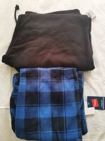 Photo of folded black joggers and blue black checkered pants with Walmart tags.