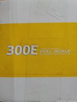 Close-up of box showing '300E Remote Control Full Scale Brushless High Speed Car' text on yellow and white background.