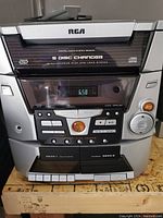 Front view of RCA stereo system showing 5 disc changer label, cassette decks, buttons, and display panel.