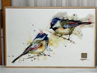 Full front view of the framed watercolor print depicting two chickadees with splashes of colorful paint, signature visible bottom right.