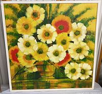 Frontal view of an original signed flower painting showing multiple large flowers in white, yellow, and orange hues with green accents, framed.