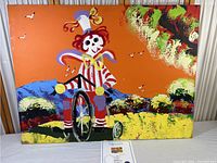 Front view of 'The Swinger' painting by PB Henrie showing the colorful skeleton figure on a bicycle against a bright landscape.