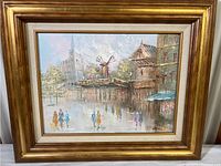 Full frontal photo of the framed oil painting showing European city scene including windmill and pedestrians.