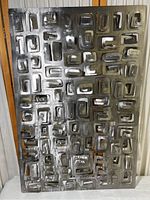 Full view of the three-dimensional rectangular patterned metal artwork with reflective surfaces.