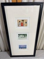 Full view of black frame containing three vertically aligned small prints with white mat.
