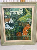 Full view of the framed Van Gogh print depicting houses by a water body.