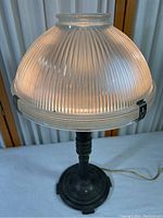 Front view of the lamp showing ridged translucent glass dome shade and metal base.