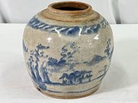 View of jar showing blue and white landscape painting, glaze with crackle and natural wear.