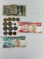 Layout of coins and banknotes from Singapore, Austria, and others on white surface, showing condition and diversity