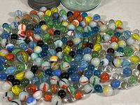 Close-up image showing large group of assorted vintage glass marbles in various colors and swirl patterns.