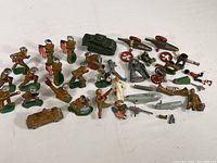 Overview of entire lot showing all metal toy soldiers, vehicles, and assorted parts including flags, artillery, and dog figure.