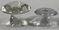 Two modern clear crystal mushroom-shaped paperweights, varying sizes, on white background