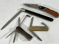 Five assorted pocket knives and multi-tools displayed on white background, showing condition and details of handles and blades.