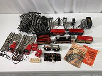 Full layout photo showing trains, track pieces, transformer, switches, control panel, and manuals