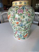 Front view of the Chinese hand painted standing vase showing the colorful floral and butterfly patterns with a soft green background and decorative yellow rim band with Chinese characters.