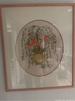 Framed hand stitched embroidery of cherry blossoms in a vase behind glass, framed in wood with mat board, measuring 22 by 28 inches.