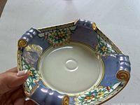 Close-up photo of the Noritake opalescent blue candy dish showing its floral design and gold accents, with some wear on corners.
