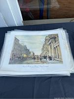 Stack of color lithographic prints featuring Royal Bridge and Waterloo Place, Edinburgh under a protective sleeve.