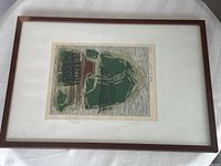 Framed woodblock print featuring abstract design with green and brown shapes, mounted with white matting in wooden frame.