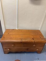 Front view of wooden blanket box with visible surface wear and scratches.
