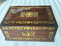 Top view of a rectangular rosewood box with gold floral inlay and engraved initials 'J.M.L.'